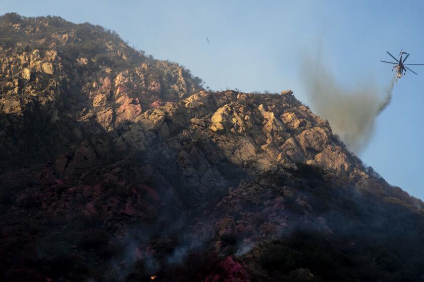 MALIBU, CALIF. -- SUNDAY, NOVEMBER 11, 2018: A helicopter drops water on a hot spot in steep terrain above Malibu Canyon Rd. on the Woolsey fire in Malibu, Calif., on Nov. 11, 2018. (Brian van der Brug / Los Angeles Times)