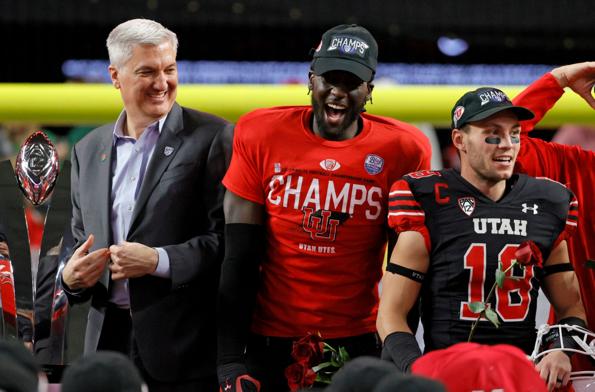 Pac-12 Commissioner George Kliavkoff stands next to Utah linebacker Devin Lloyd and wide receiver Britain Covey.