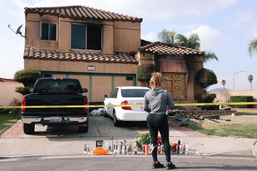 Riverside, CA - November 28: A woman looks at a memorial outside a home where the deaths of three people were found Friday in a burning home at a residence on Monday, Nov. 28, 2022 in Riverside, CA. They are thought to be connected to the attempted abduction of a teenage girl. (Dania Maxwell / Los Angeles Times)