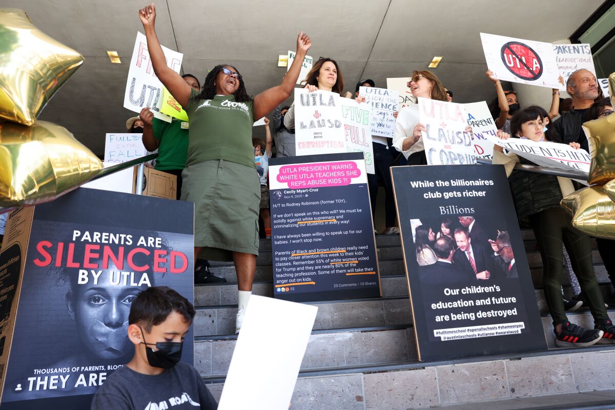 People hold signs during a rally calling for L.A. schools to reopen fully.