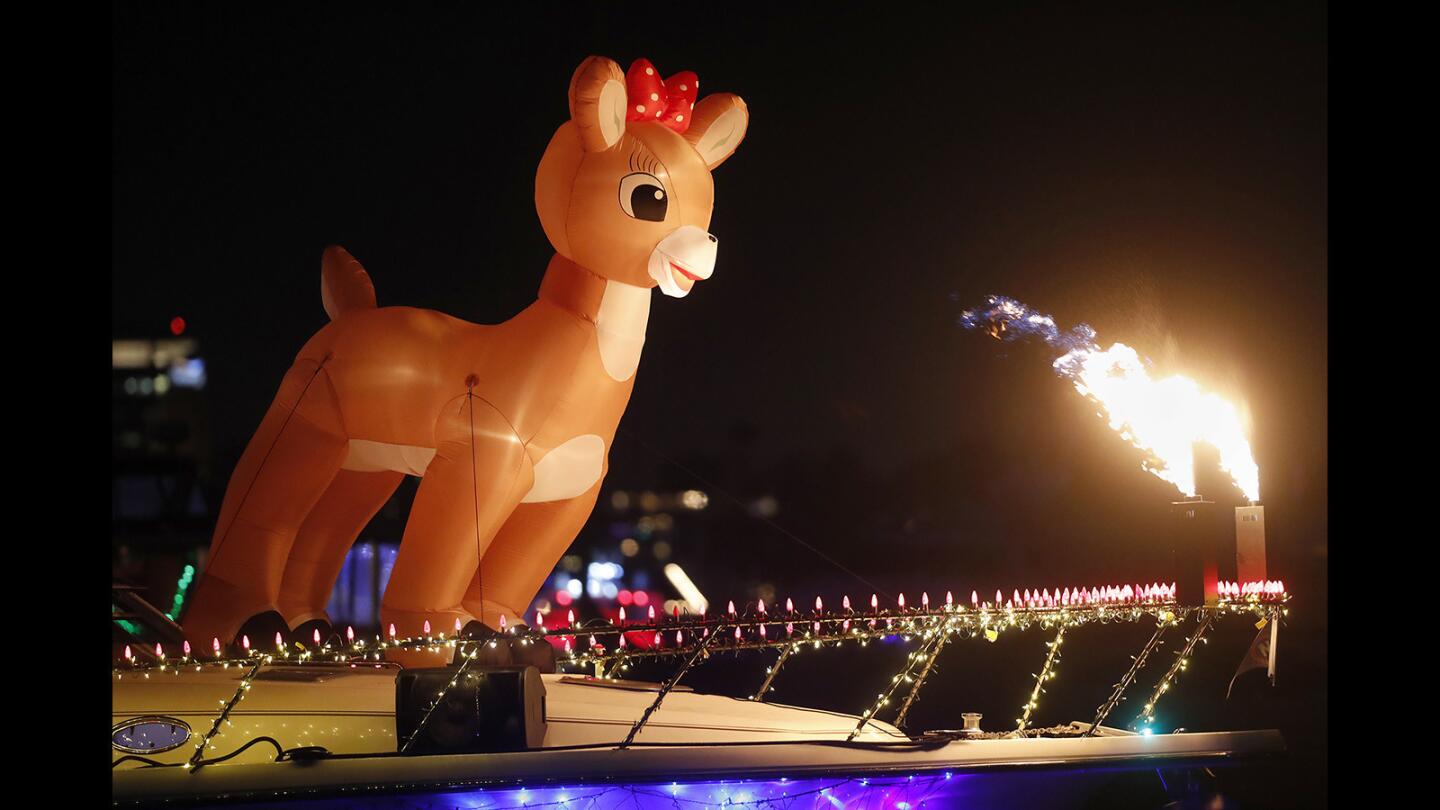 A boat decorated with a giant reindeer and flames cruises along during opening night of the 109th Newport Beach Christmas Boat Parade and Ring of Lights on Wednesday.