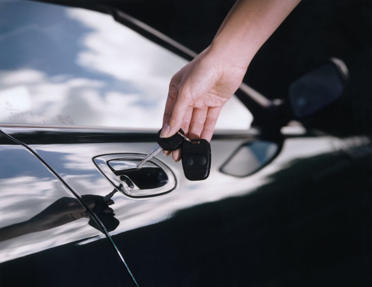 A hand holding a keychain near a car door