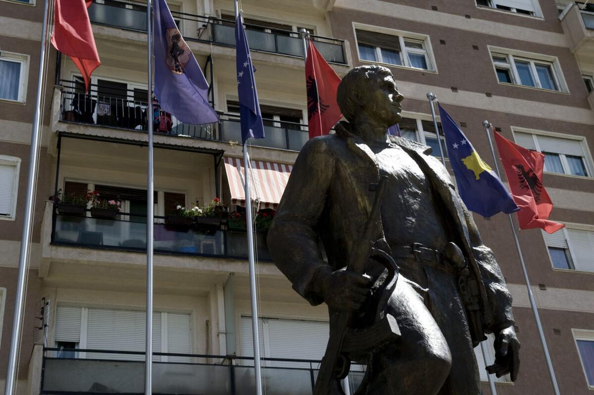 Kosovo and Albanian flags flying behind a statue of a former Kosovo Liberation Army commander in Pristina, the Kosovo capital. A special prosecutor reported Tuesday that war crimes charges are pending against senior KLA leaders.