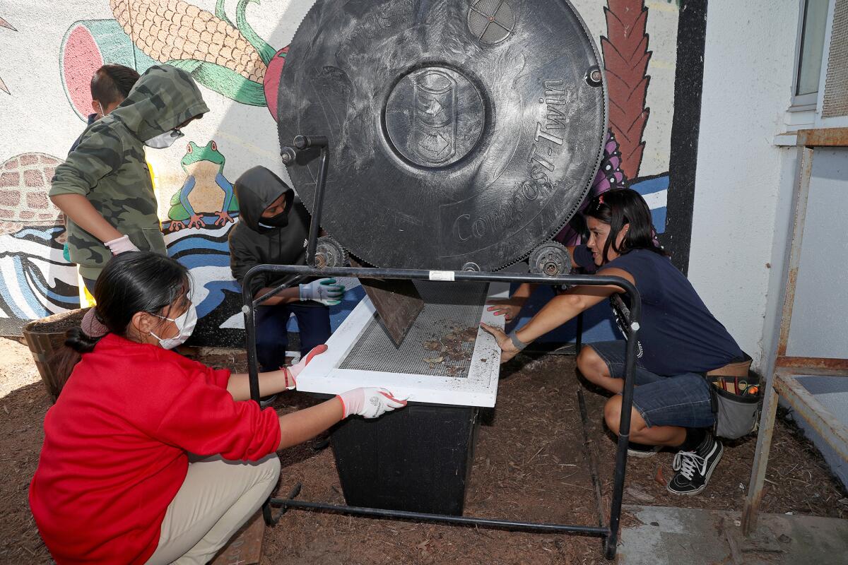 Science teacher Monique Sweet, right, shows sixth-graders how to use a compost bin at Costa Mesa's Rea Elementary School.