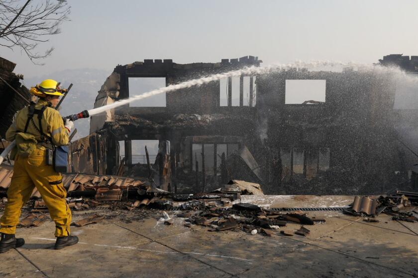 Bell Canyon, CA NOVEMBER 10, 2018: Firefighter Brittney Bebek, (cq) with LA City Station 93 puts out hot spots on Hitching Post Lane in Bell Canyon, CA November 10, 2018. Many homes were lost to the Woolsey fire. Other homes even across the street from the burned out property were untouched by fire. (Francine Orr/ Los Angeles Times)