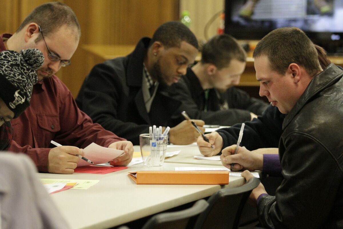 In this Jan. 29, 2015 photo, people fill out applications during a public safety job fair at City Hall in Saginaw, Mich.
