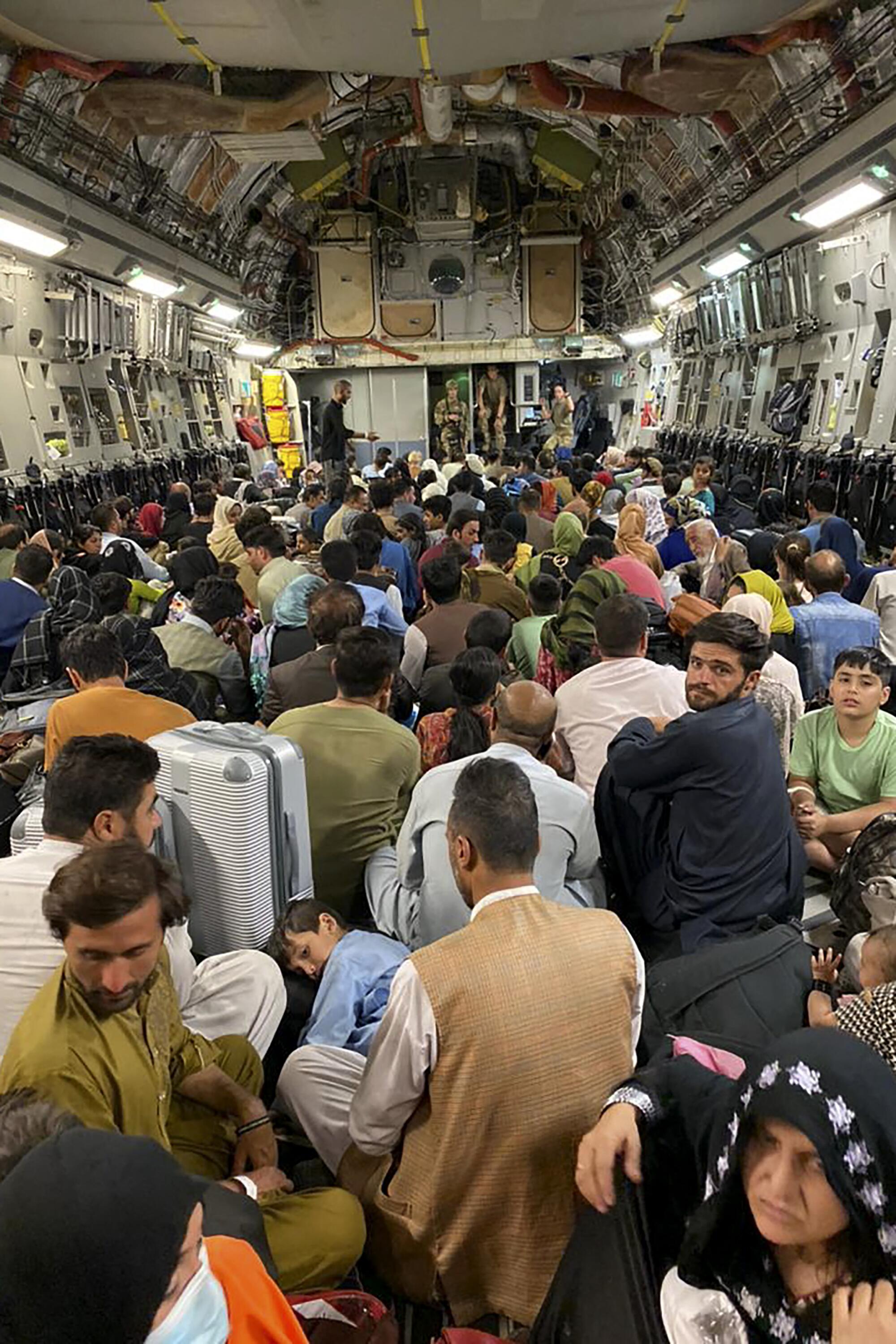 Afghan people sit inside a U.S. military aircraft to leave Afghanistan, at the military airport in Kabul.