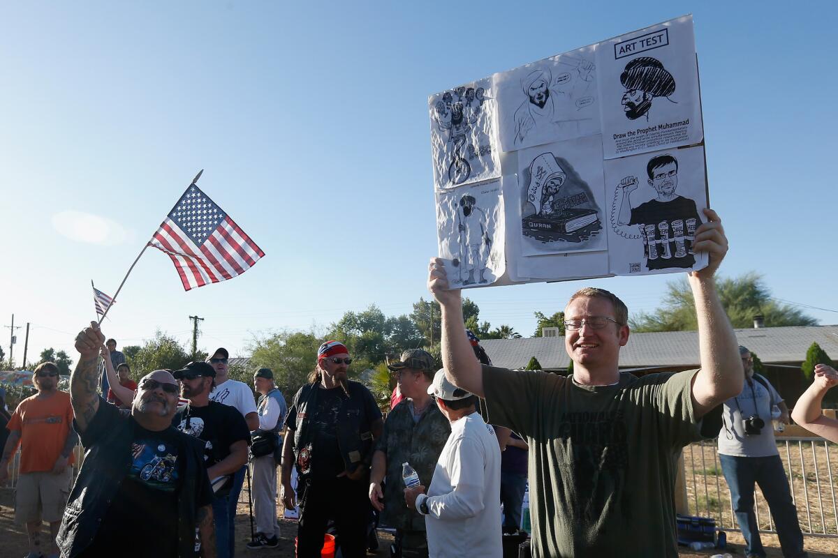 Demonstrators hold up signs depicting the prophet Muhammad as they stage an anti-Islam protest outside a mosque in Phoenix.