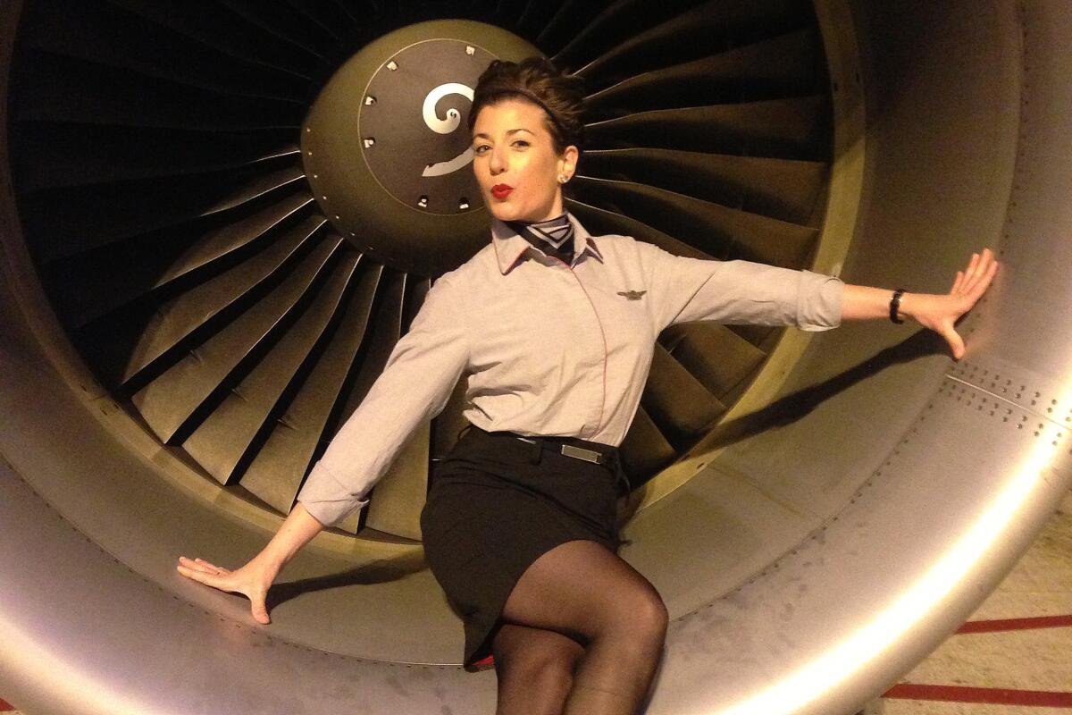 T.J. Newman sits in front of a turbine engine dressed as a flight attendant.