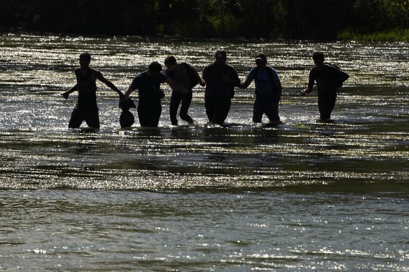 Migrants join hands as they cross the Rio Grande from Mexico into the U.S., Thursday, Sept. 21, 2023, in Eagle Pass, Texas. (AP Photo/Eric Gay)