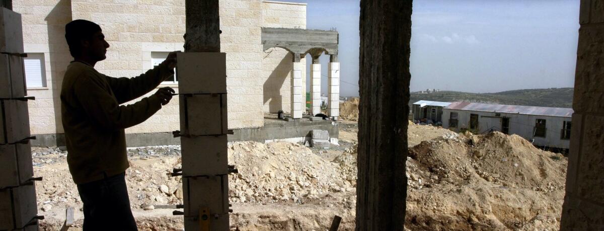 In this file photo from March 8, 2005, a worker builds a new structure in the illegal outpost of Amona in the central West Bank. To satisfy a court order, settlers began tearing up an access road to the settlement on Tuesday.