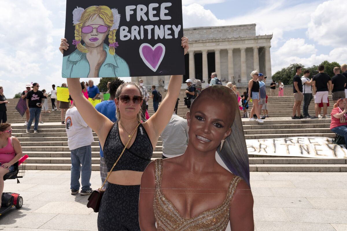 FILE - In this July 14, 2021 file photo Maggie Howell supporter of pop star Britney Spears protests next to a Britney Spears cardboard cutout at the Lincoln Memorial, during the "Free Britney" rally, in Washington. Spears' fight to end the conservatorship that controlled vast aspects of her life is putting the spotlight on ongoing efforts in U.S. states to reform laws that advocates say too often harm the very people they were meant to protect. (AP Photo/Jose Luis Magan,File)