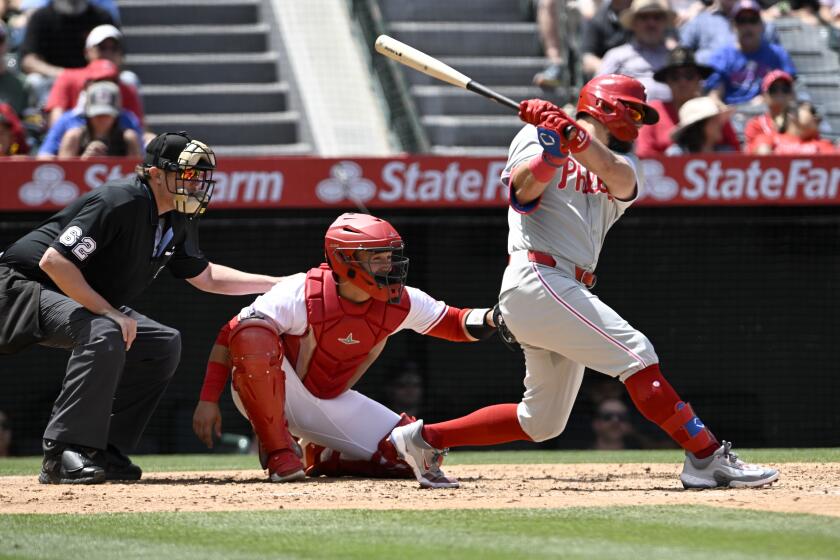 Philadelphia Phillies designated hitter Kyle Schwarber, right, hits a two-RBI single next to Los Angeles Angels catcher Matt Thaiss and home plate umpire Chad Whitson (62) during the second inning of a baseball game in Anaheim, Calif., Wednesday, May 1, 2024. (AP Photo/Alex Gallardo)