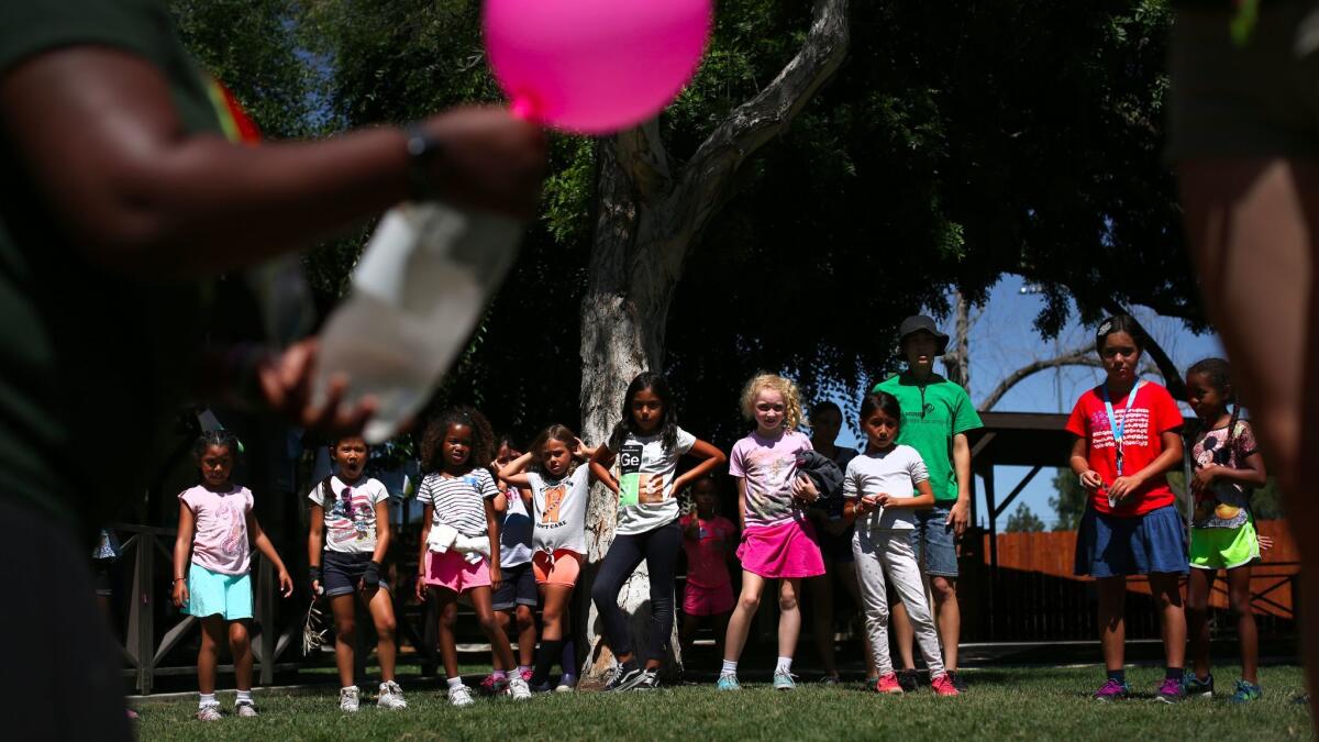 Girl Scouts watch an experiment during a summer day camp in Long Beach. Starting in 2018, they'll be able to earn badges for cybersecurity.