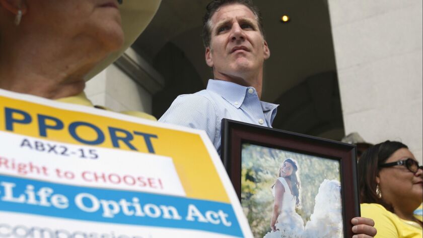 In this Sept. 24, 2015, file photo, Dan Diaz holds a photo of his late wife, Brittany Maynard, during a rally calling for California Gov. Jerry Brown to sign right-to-die legislation at the Capitol in Sacramento. A state judge threw out the law Tuesday.