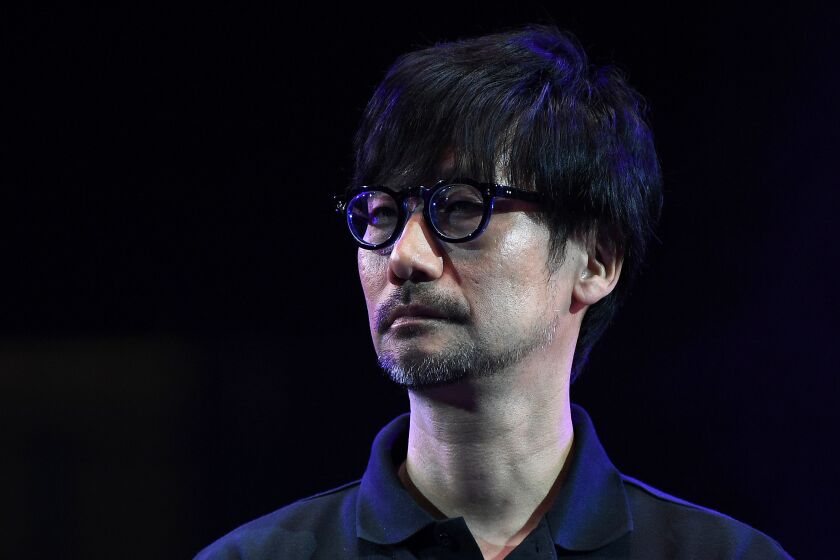A man with a bowl cut wearing glasses and a dark shirt. 