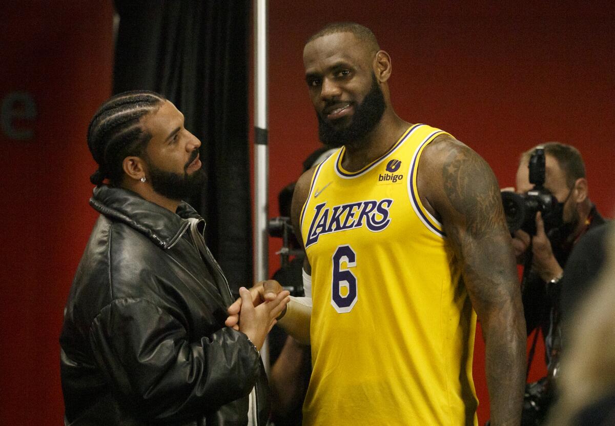Drake, left, and LeBron James shake hands and talk after an NBA game.