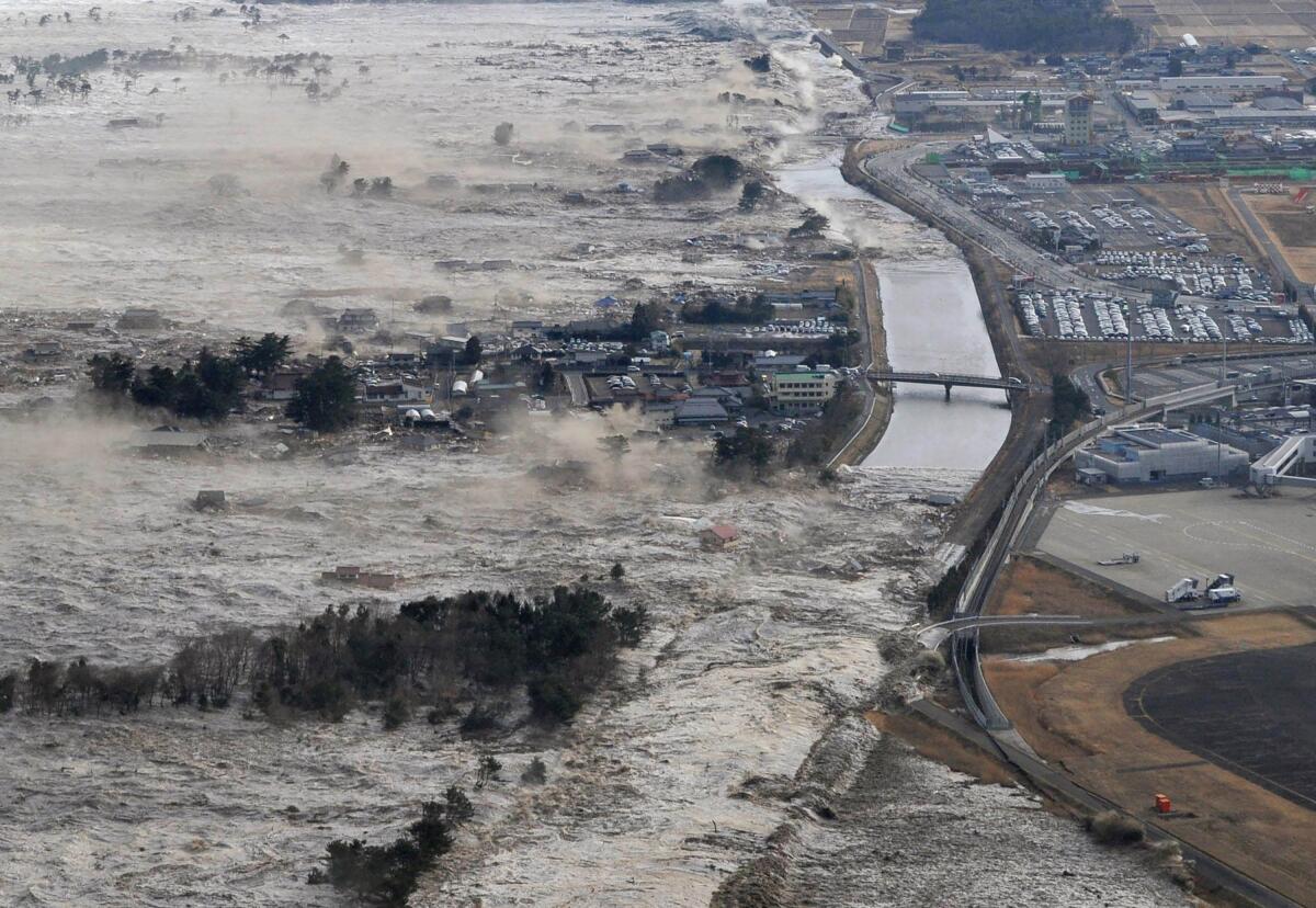 FILE - In this March 11, 2011, file photo, earthquake-triggered tsunami sweeps shores along Iwanuma, Miyagi prefecture, northern Japan. March 11, 2020 marks the 10th anniversary of a massive earthquake, tsunami and nuclear disaster that struck Japan's northeastern coast. (Kyodo News via AP, File)