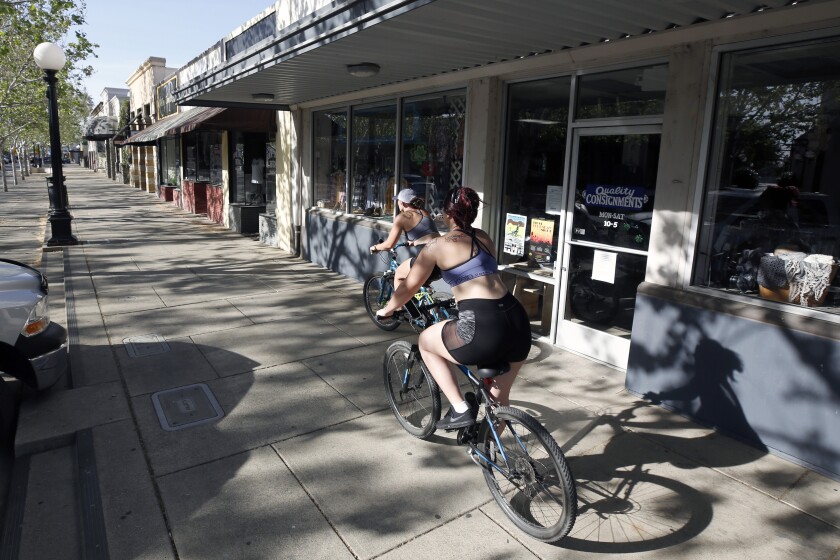 A pair of bicyclists ride past closed businesses on Plumas Street in Yuba City, Calif., in late April during the coronavirus outbreak.