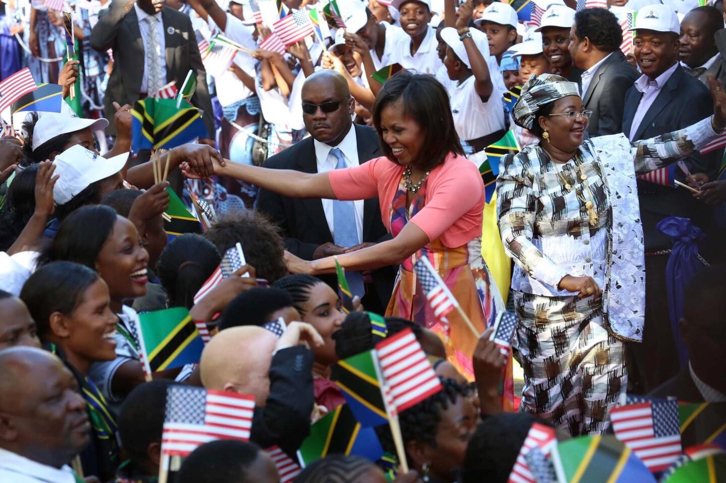U.S. First lady Michelle Obama and Tanzanian first lady Salma Kikwete greet Tanzanian people during an official arrival ceremony in Dar Es Salaam