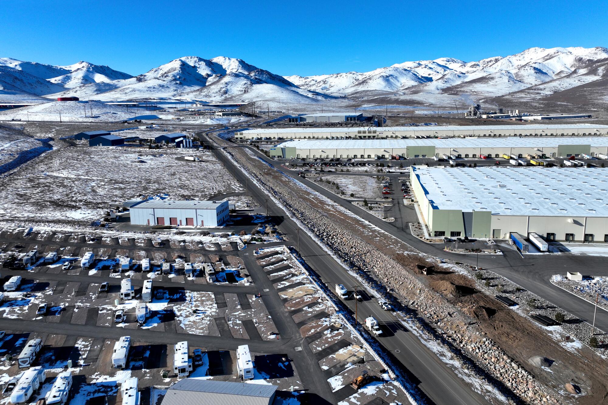 Warehouses and parking areas next to snowy mountains.