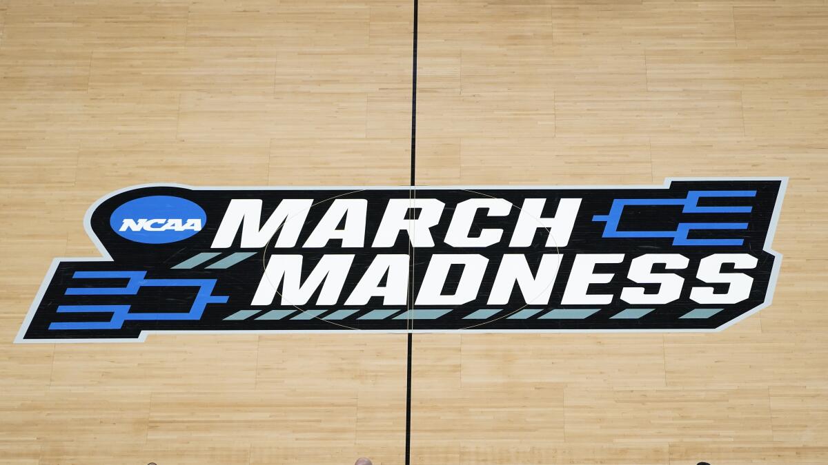 FILE - In this March 20, 2021, file photo the March Madness logo is shown on the court during the first half of a men's college basketball game in the first round of the NCAA tournament at Bankers Life Fieldhouse in Indianapolis. A Supreme Court case being argued this week amid March Madness could erode the difference between elite college athletes and professional sports stars. (AP Photo/Paul Sancya, File)