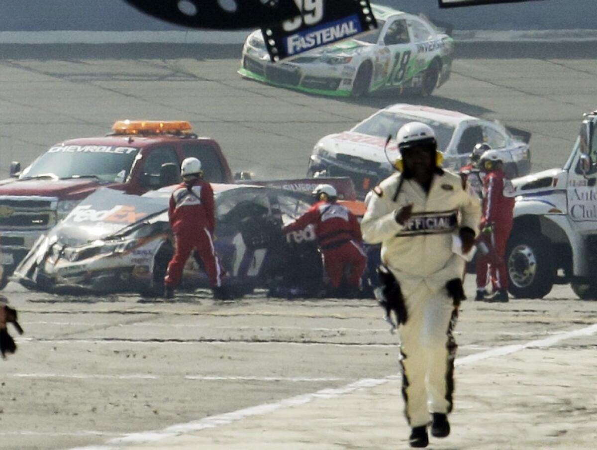 Rescue workers tend to the wreckage of the No. 11 FedEx Express Toyota driven by Denny Hamlin after he collided with Joey Logano on the final lap of the NASCAR Sprint Cup series auto race in Fontana on Sunday.
