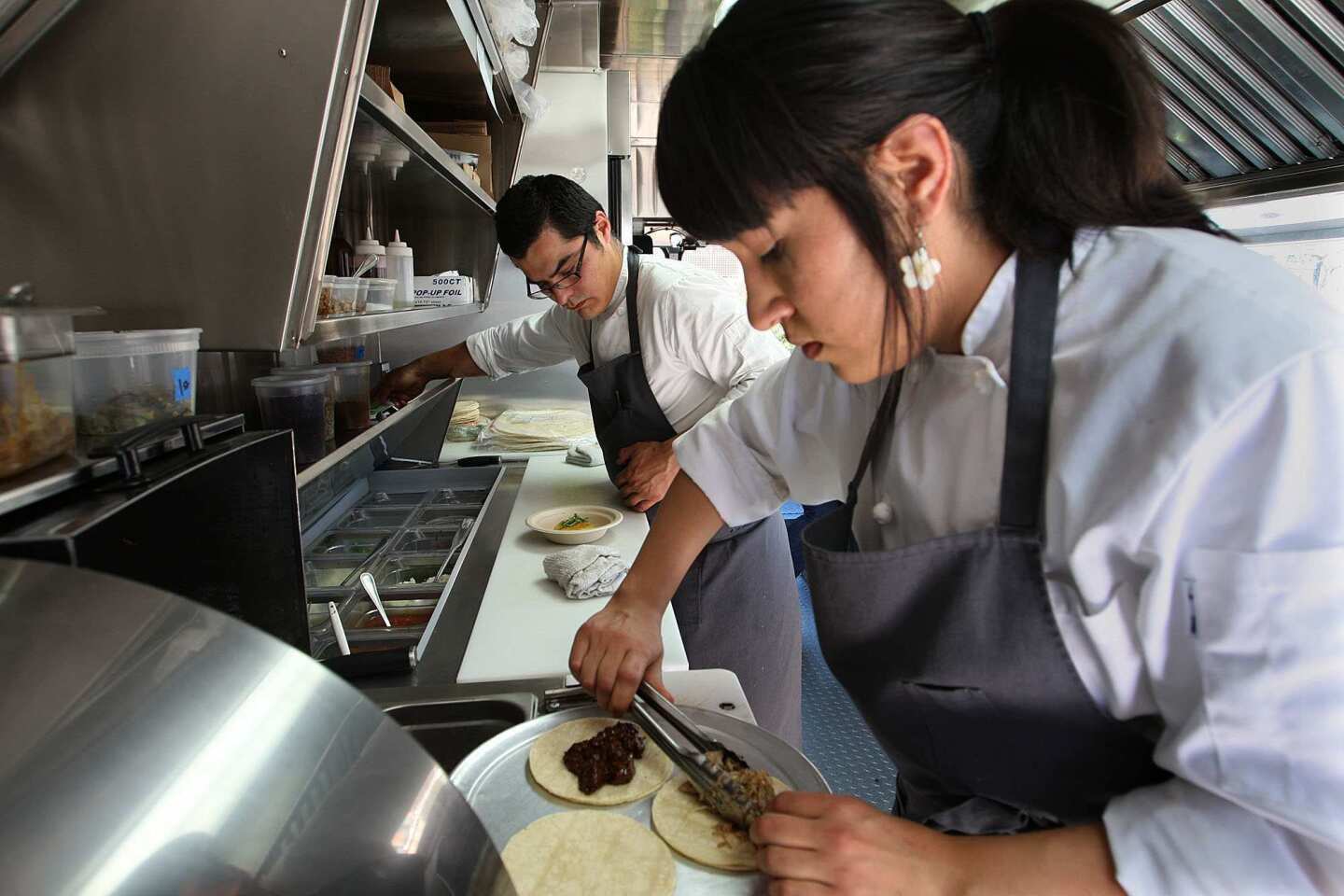 Carlos Salgado and Andrea Machuca prepare orders inside the truck, which also helps in Salgado's catering business.