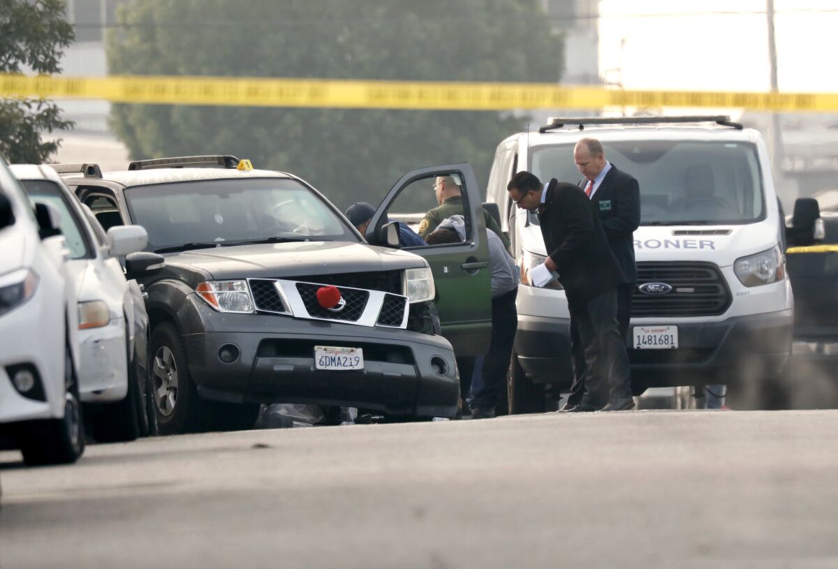 Officials study an SUV with front-end damage in a street. 