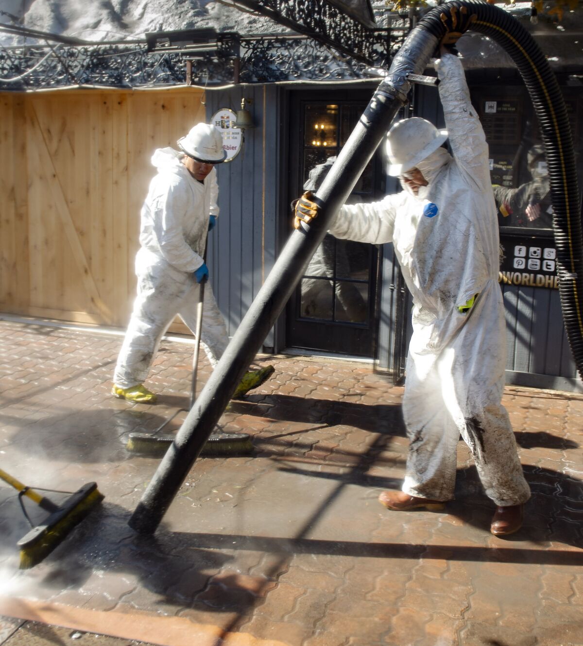 On Sunday, October 6, 2019 contract crews clean up the aftermath of an electrical vault explosion that happened Saturday night Oct. 5, at the Old World Village in Huntington Beach, Calif., during an Oktoberfest celebration. At least five people were injured in the blast. (Mindy Schauer/The Orange County Register via AP)