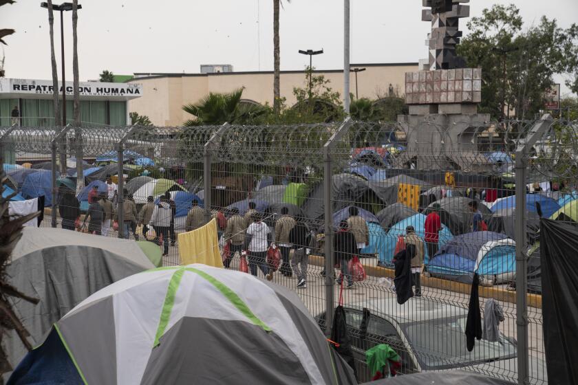 Deportees sent back to Mexico walk to the Human Repatriation facilities next to an encampment where asylum seekers live near the Gateway International Bridge as seen on Friday, Nov. 22, 2019 in Matamoros, Mexico. Verónica G. Cárdenas / For The Times