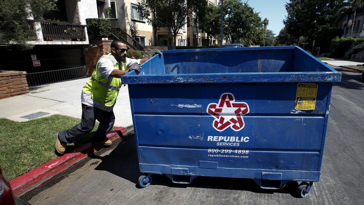 The Los Angeles City Council voted this week to rework its much criticized commercial trash pickup program, known as RecycLA. An employee with Athens Services, one of the program's contractors, moves a trash bin in West Los Angeles in 2017.