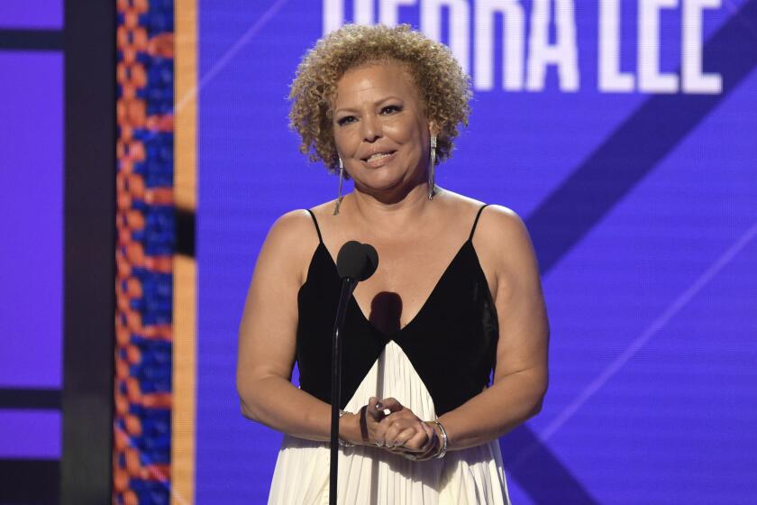 A woman with short curly hair accepts an award onstage