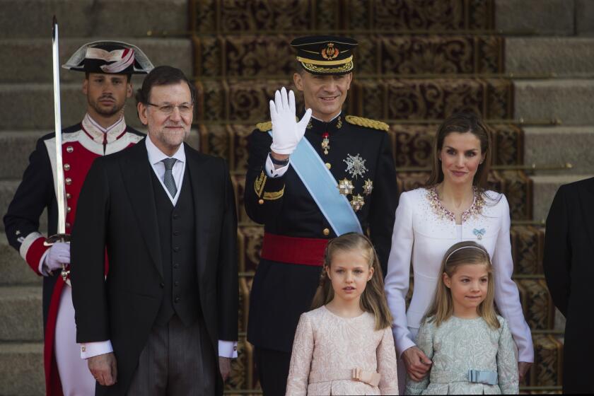 King Felipe VI waves as the royal family arrives at parliament in Madrid. With the king are Queen Letizia and princesses Leonor, bottom left, and Sofia. At far left is Spanish Prime Minister Mariano Rajoy.