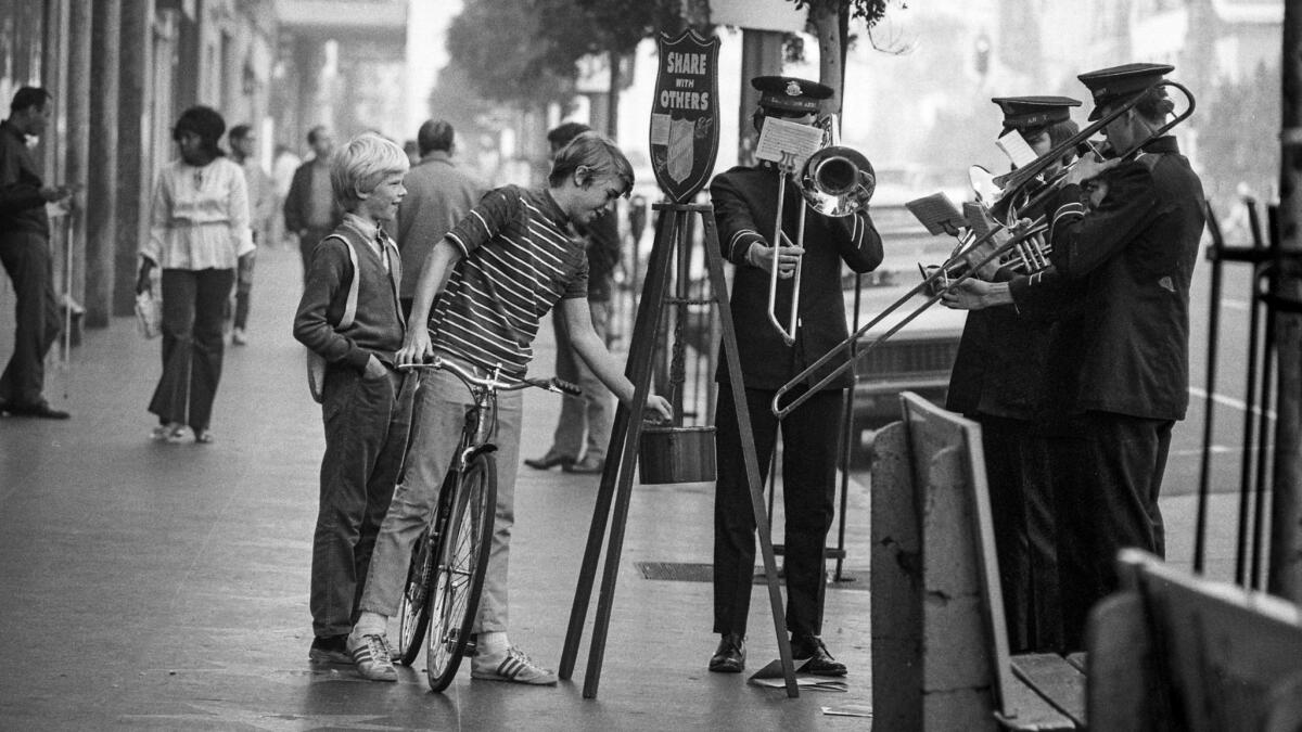 Dec. 20, 1971: Youth on bicycle drops some change into Salvation Army kettle.