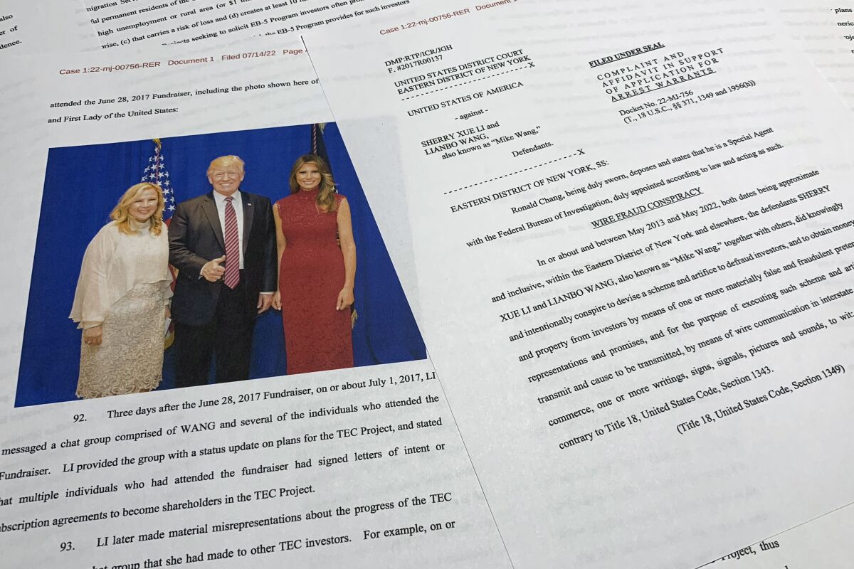 The complaint and affidavit in support of an arrest warrant against Sherry Xue Li and Lianbo "Mike" Wang is photographed on Monday, July 18, 2022. The two have been charged with funneling foreigners' money into political donations that bought access to an exclusive dinner with then-President Donald Trump. One of the photos contained in the affidavit shows Trump and first lady Melania Trump posing for a photo with Li during a fundraiser on June 28, 2017. (Department of Justice via AP)