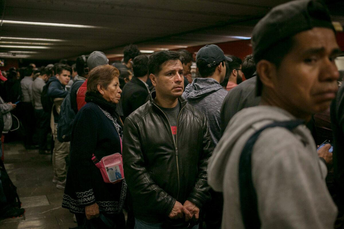 Victor Cruz Ortega, center, waits for the train during his morning commute in Mexico City. Cruz was deported from California two months ago, leaving behind his entire family, including his wife, daughter and son.