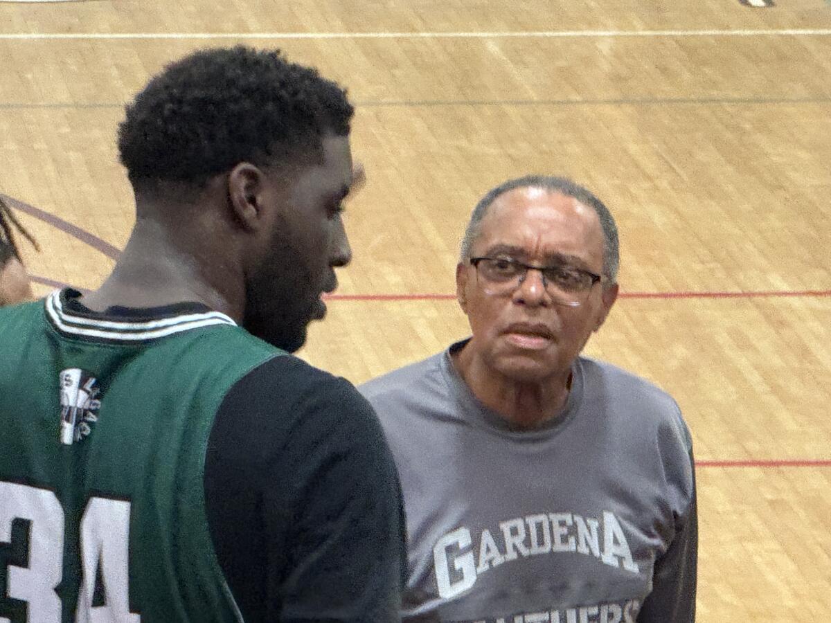 Gardena coach Ernie Carr looks up to 6-foot-11 Promise Madubugwu while standing on the sideline.