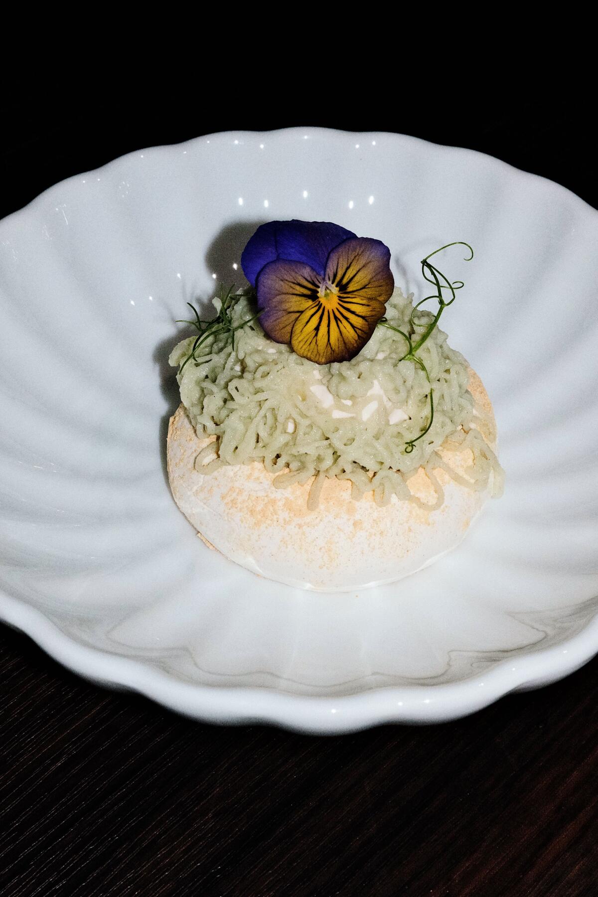 A vertical photo of Korean restaurant Danbi's Mont Holla dessert in a white bowl and adorned with an edible flower.