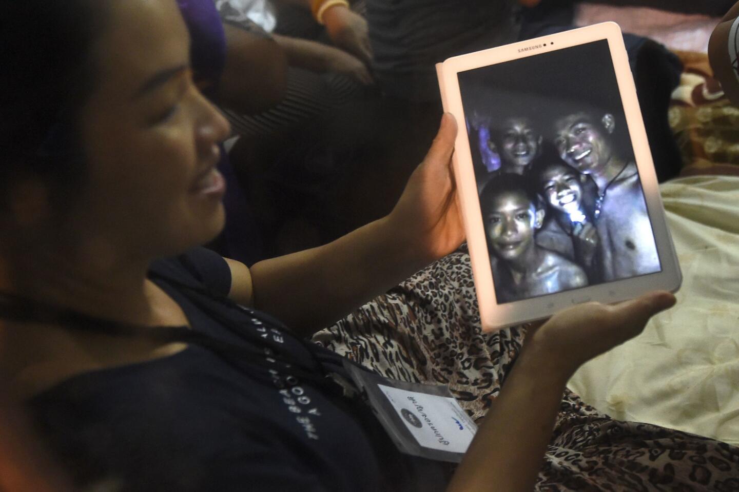 A happy family member shows the latest pictures of the missing boys taken by rescue divers inside Tham Luang cave.
