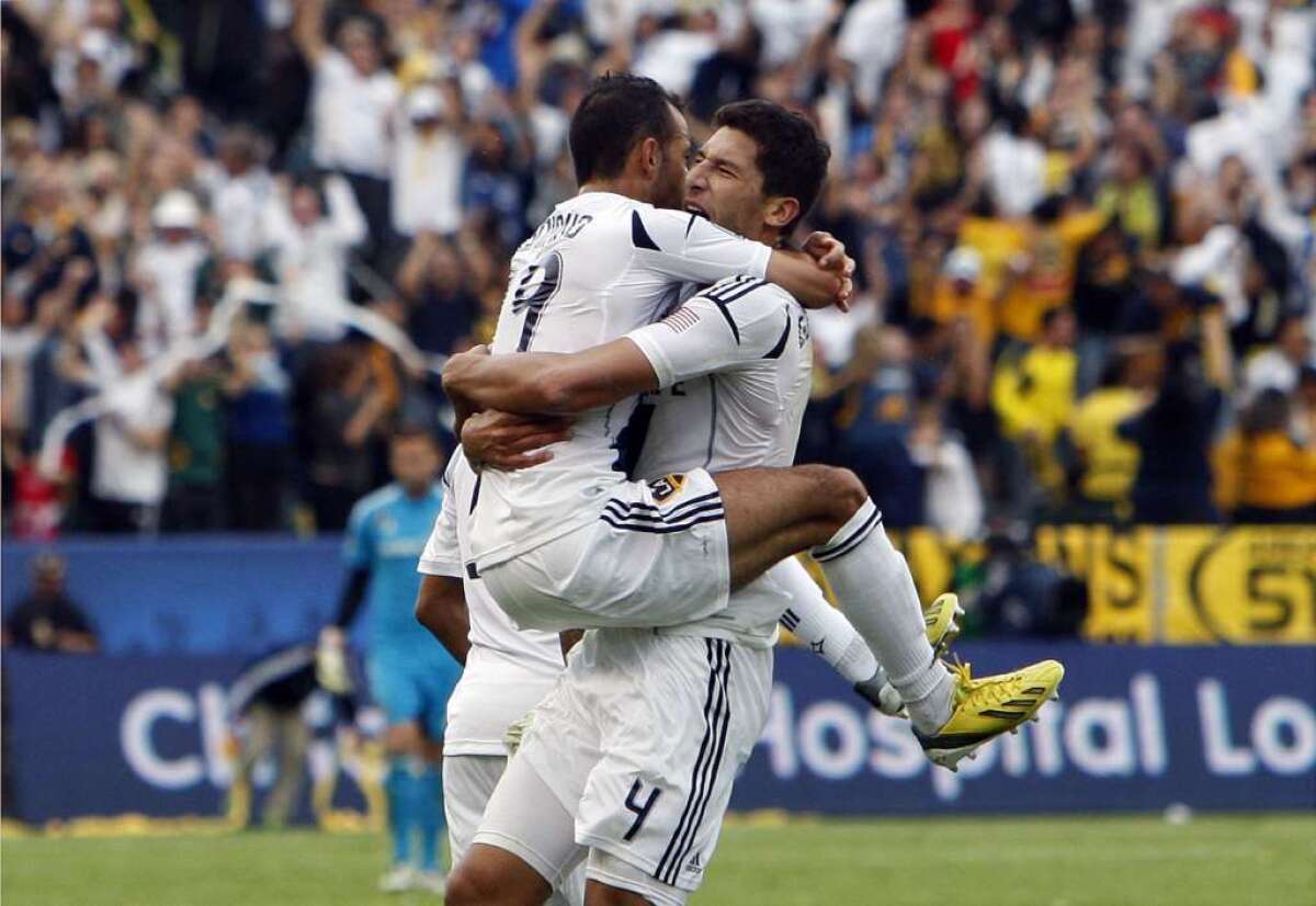 The Galaxy's Juninho leaps into the arms of Omar Gonzalez during the MLS Championship against the Houston Dynamo.