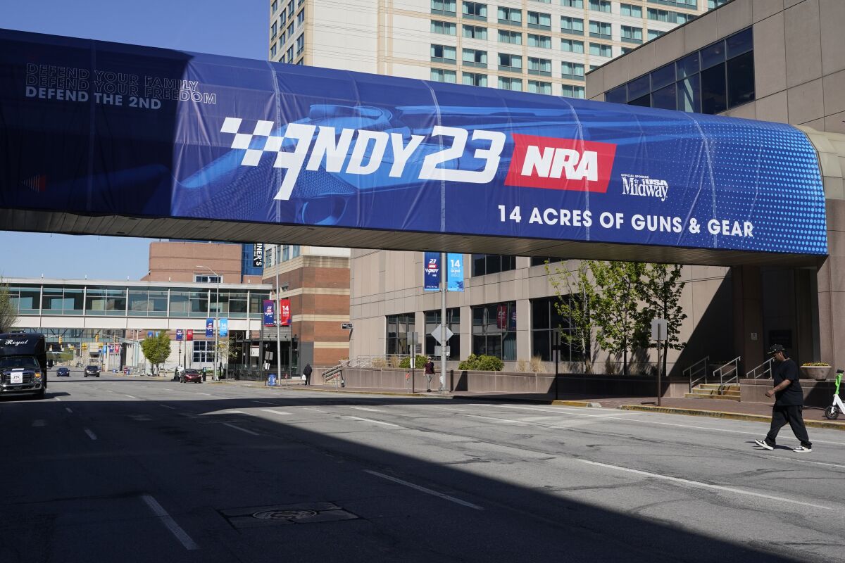 A pedestrian walks under a sign advertising the NRA convention  in Indianapolis. 