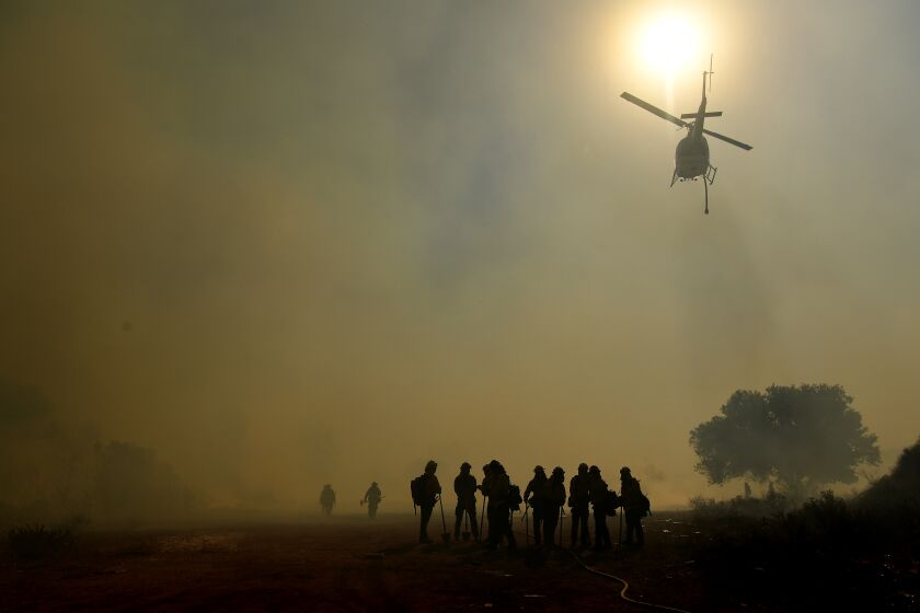 -CA-MAY 24, 2021: A firefighting helicopter prepares to drop water on the Jurupa Valley Fire as it burns over 100-acres in Riverside Monday. (Wally Skalij / Los Angeles Times)