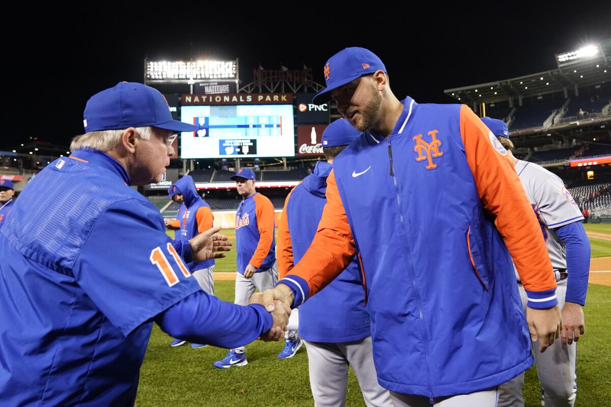 New York Mets manager Buck Showalter, left, shakes hands with starting pitcher Tylor Megill after an opening day baseball game against the Washington Nationals at Nationals Park, Thursday, April 7, 2022, in Washington. The Mets won 5-1. (AP Photo/Alex Brandon)