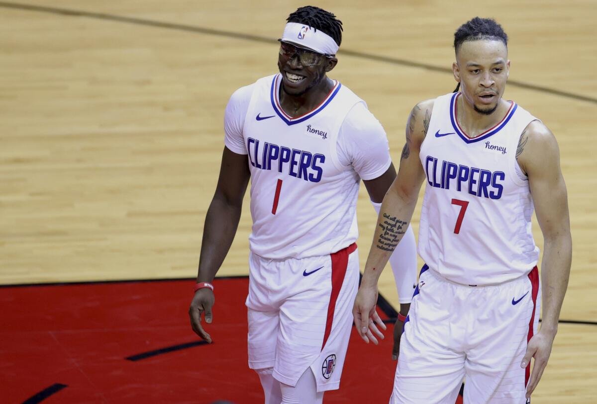 The Clippers' Reggie Jackson, left, and Amir Coffey walk to the bench April 23, 2021, in Houston.