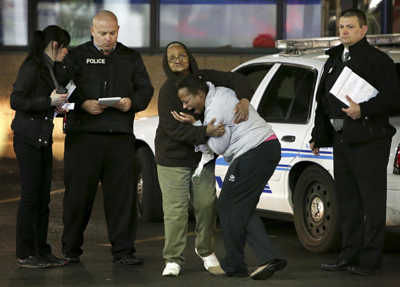 Toni Martin, front center, cries out as she talks to police at the scene where she says her son was fatally shot Tuesday at a gas station in Berkeley, Mo.