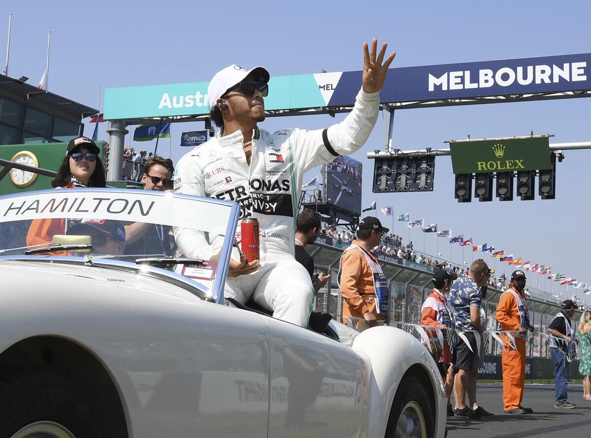 In this March 17, 2019, file photo, Mercedes driver Lewis Hamilton of Britain waves as the drivers parade begins ahead of the Australian Grand Prix in Melbourne, Australia. The start of the 2021 Formula One season has been delayed after the Australian Grand Prix was postponed because of the coronavirus pandemic. The Australian race in Melbourne has been rescheduled from March 21 to November 21. (AP Photo/Andy Brownbill, File)