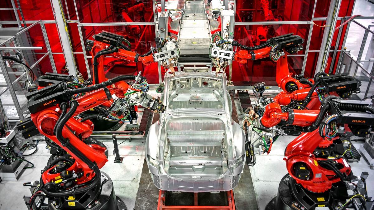 Robots work on Tesla cars as they move down the Fremont, Calif., factory line in 2015.
