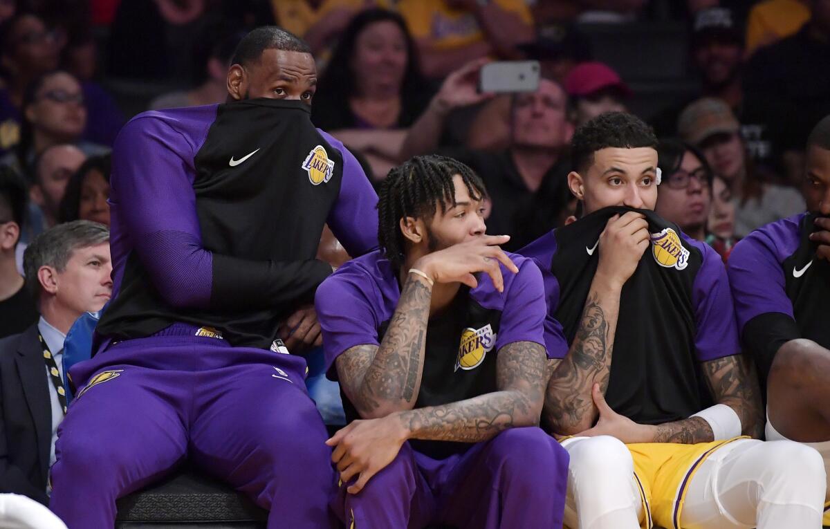 Los Angeles Lakers forward LeBron James, left, sits on the bench with forward Brandon Ingram, center, and forward Kyle Kuzma during the second half of an NBA basketball game against the Denver Nuggets Tuesday, Oct. 2, 2018, in Los Angeles.