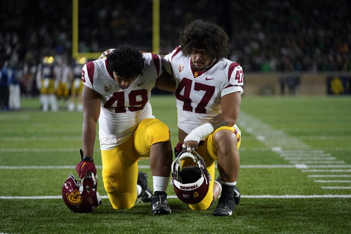 USC's Tuli Tuipulotu (49) and Stanley Ta'ufo'ou (47) kneel in the end zone in a moment of prayer.